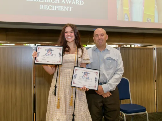 Cecilia Roessle standing with Dr. Ricoy, displaying Outstanding Senior Award and Diploma.